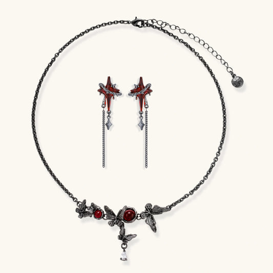 Gothic jewelry set with red resin cross pendants wrapped in dark metal chains on cream background.