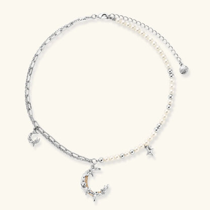 Silver-toned crescent moon pendant with star accents on pearl and chain necklace against white background.