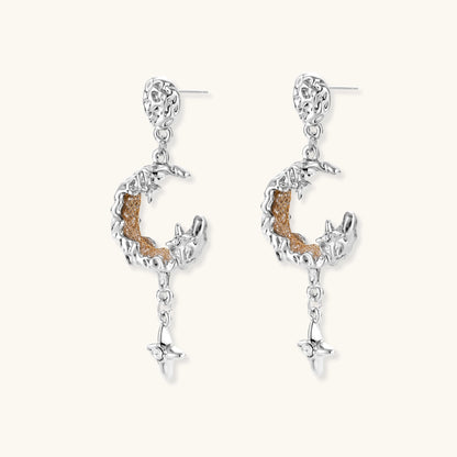 Detailed eco-brass dangle earrings featuring crescent moons with gold rope details and dangling star charms on white background.