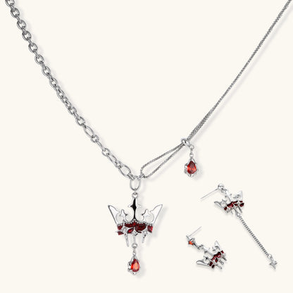 Silver-tone crown pendant with red zirconia stones and matching asymmetrical earrings on cream background