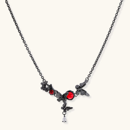 Dark oxidized metal necklace featuring red resin stones set in decorative leaf vine design with crystal drop pendant.