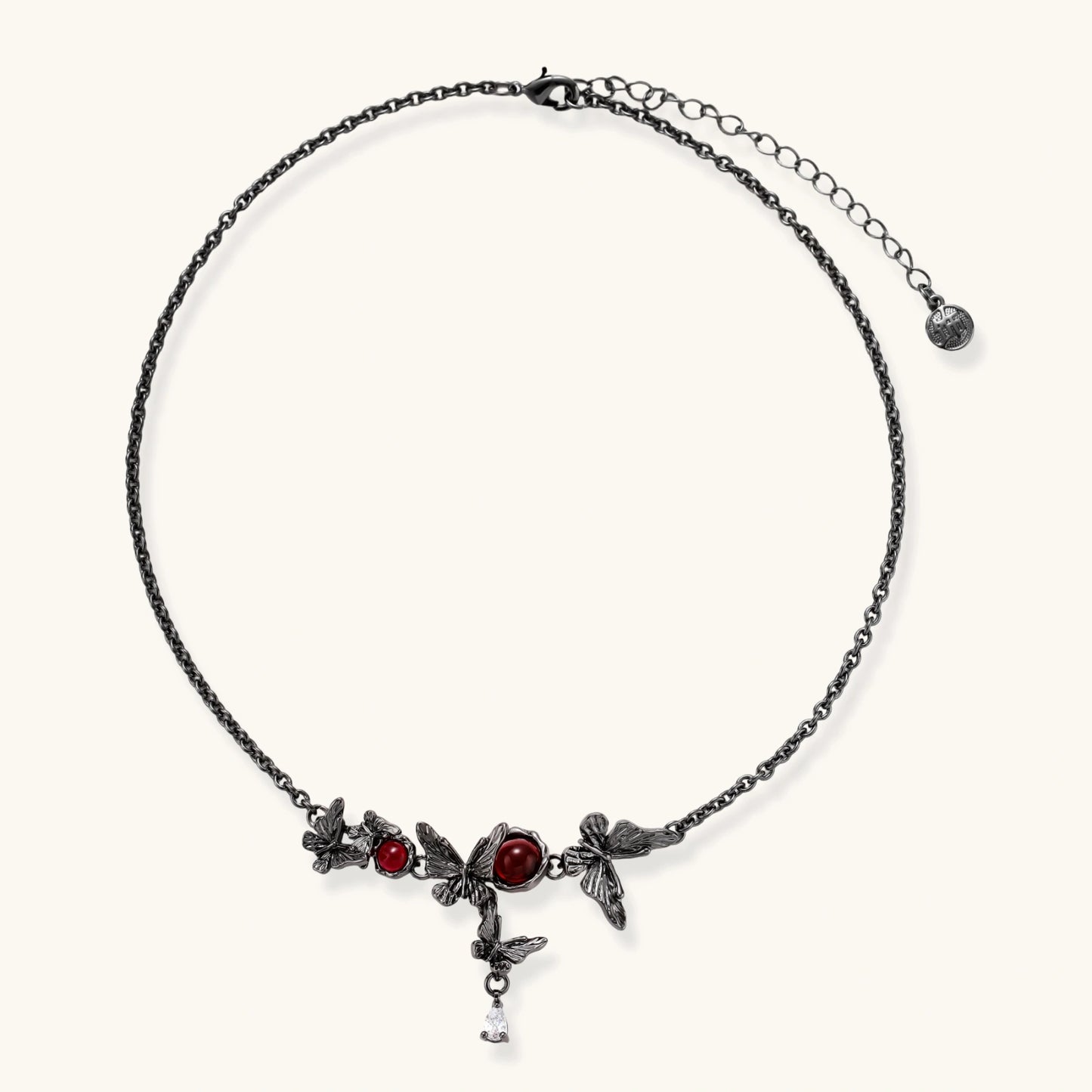 Dark oxidized metal necklace featuring red resin stones set in decorative leaf vine design with crystal drop pendant.