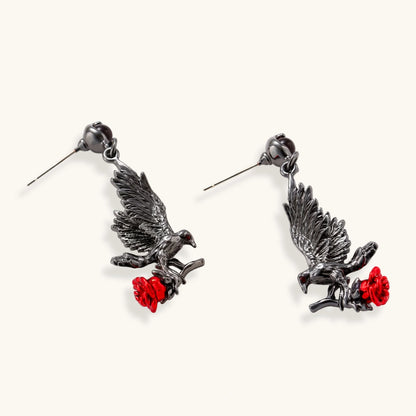 Dark gunmetal jewelry set featuring detailed raven pendants carrying red enamel roses with layered pearl and chain necklaces