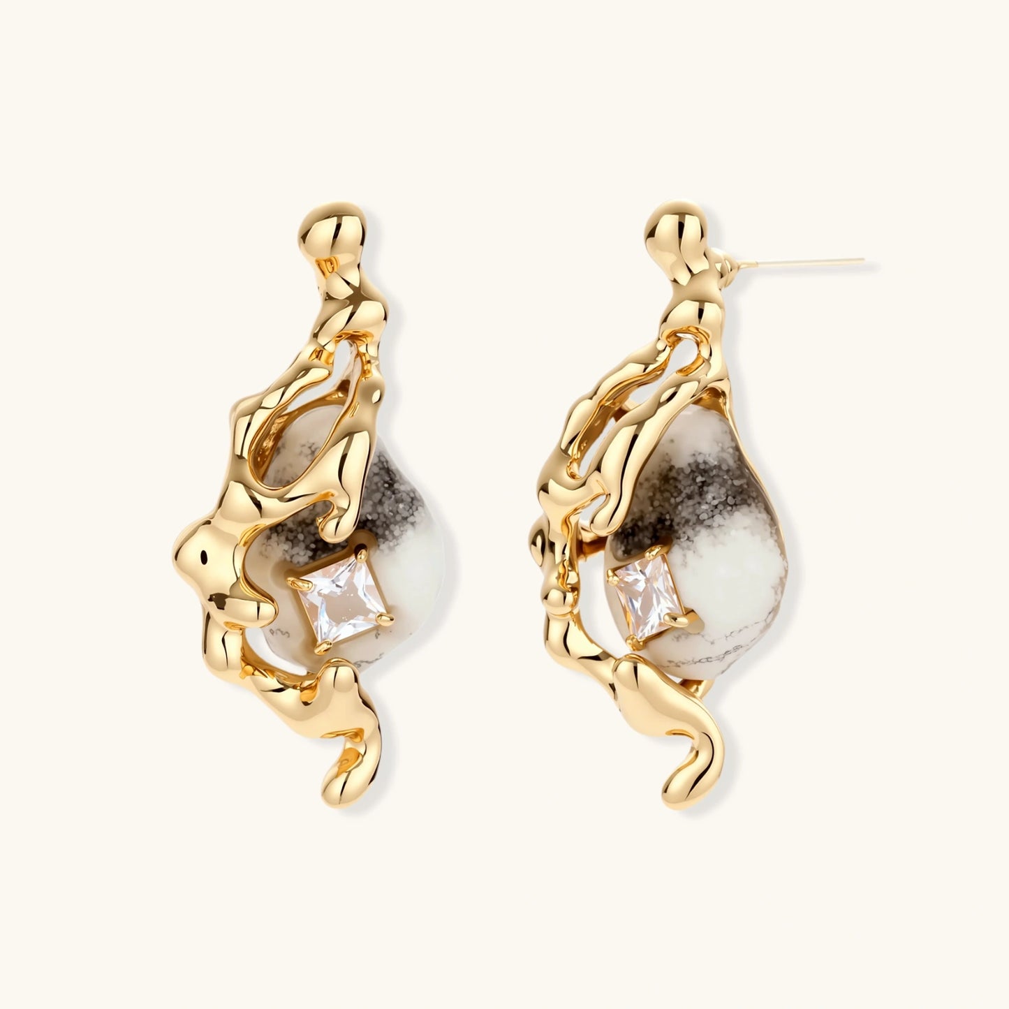 Close-up of metallic dragon-wrapped earrings with marbled resin stones on white background